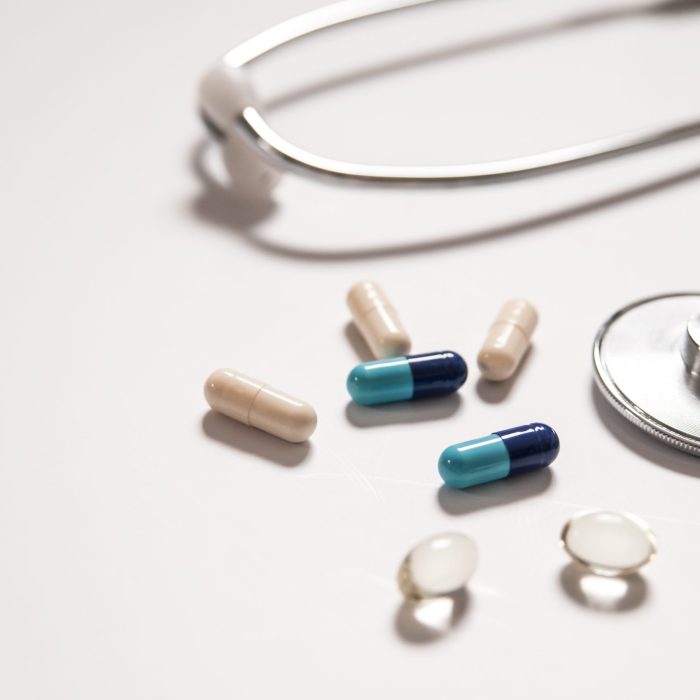 stethoscope on white background with mix pills isolated. Medical background with pills.  The stethoscope is next to the pills, isolated on white background